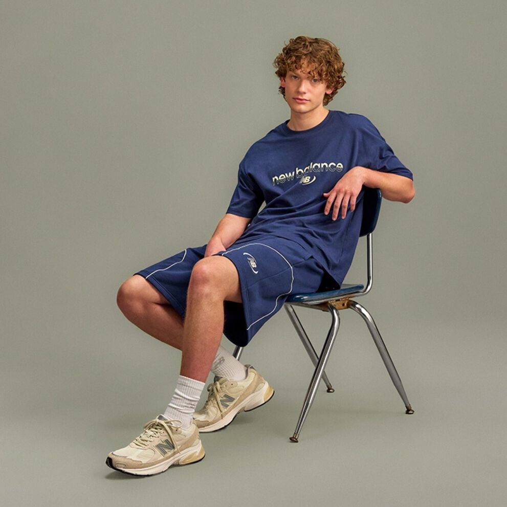 The person is wearing a light gray athletic T-shirt with blue text partially visible reading &ldquo;We&rsquo;re In It For The Long Run.&rdquo; 